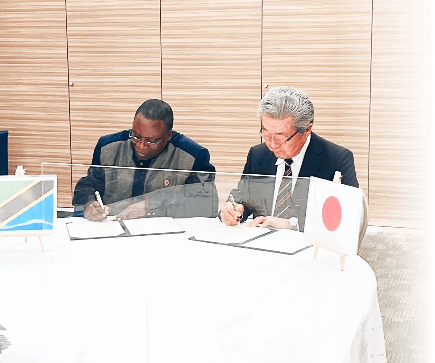 日本人1名と外国の方1名が書類にサインする画像